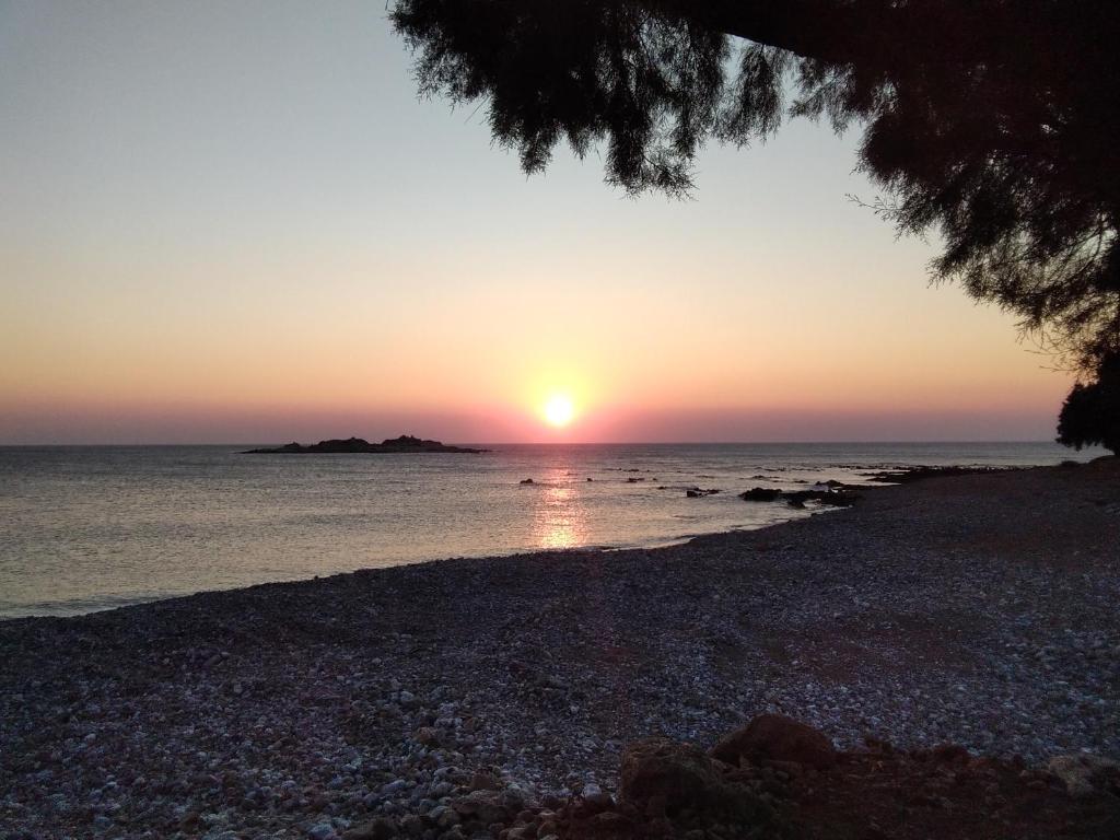 a sunset over the ocean with a rocky beach at Sea Side House Rapanas in Falasarna