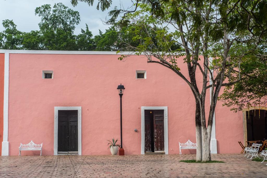 a pink building with a tree in front of it at IMIX Hotel in Valladolid