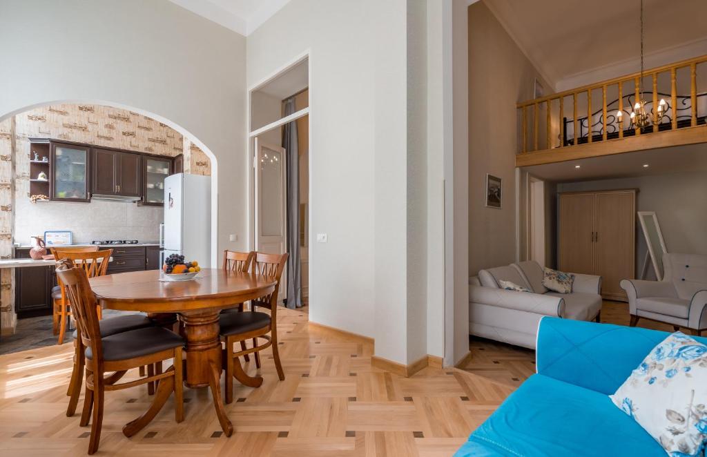 cocina y sala de estar con mesa de madera y sillas en MMA Apartment en Tiflis