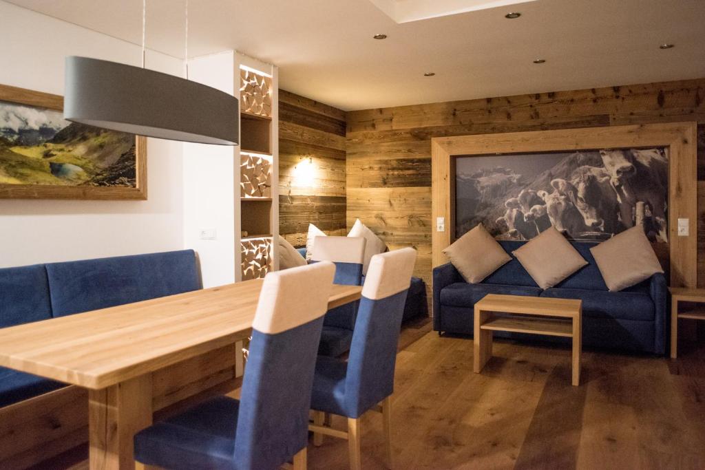 a dining room with a wooden table and blue chairs at Haus Silvretta NOVA in Schruns