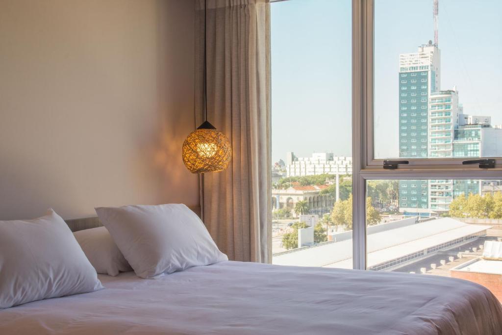 a bedroom with a bed and a large window at Hotel Ciudadano Suites in Montevideo