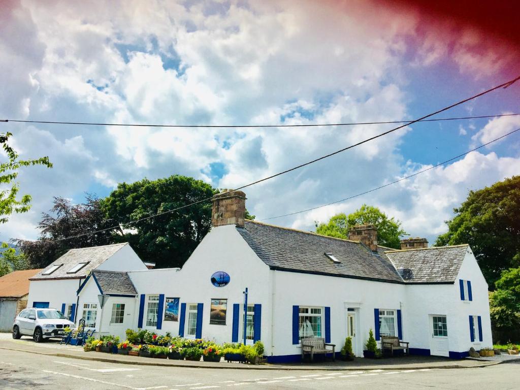 a white house with blue shutters on a street at Ladysmith Guest House in Ullapool