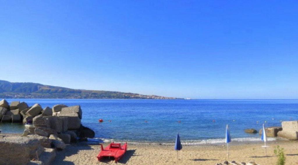 einen Strand mit einem roten Picknicktisch und dem Meer in der Unterkunft il Faro di Zancle, la Porta della Sicilia in Messina