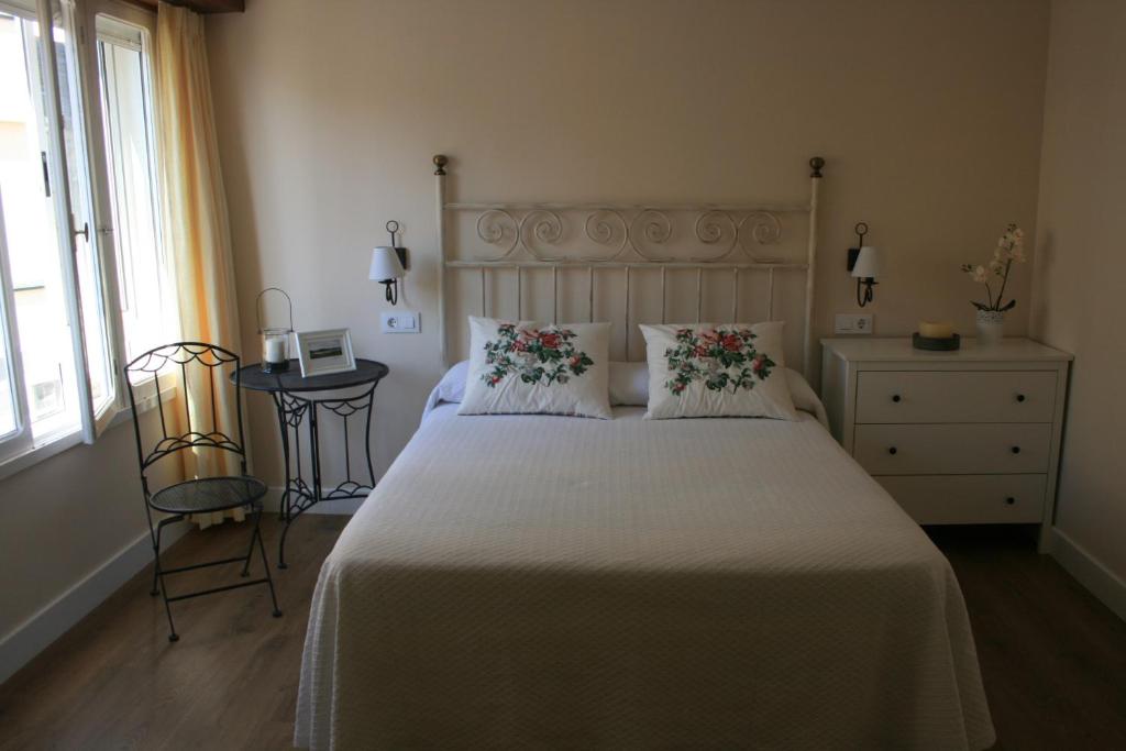 una camera da letto con un grande letto bianco con fiori di Las Palomas a O Porto de Espasante