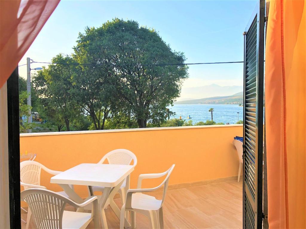 a table and chairs on a balcony with a view of the water at Apartments Branka in Gornji Karin