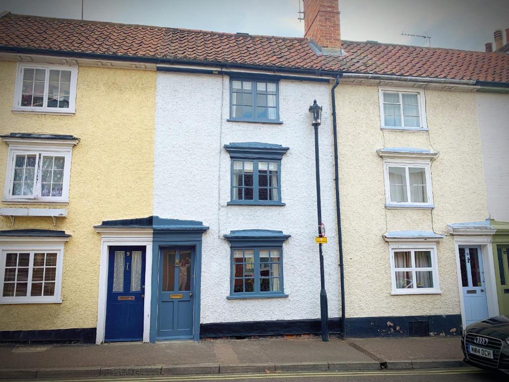 een geel en wit huis met blauwe deuren en ramen bij Sweet & cosy 10 Bridewell Cottage with parking available upon request in Bury Saint Edmunds
