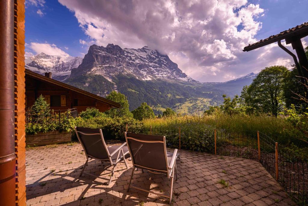twee stoelen op een patio voor een berg bij Bisi in Grindelwald