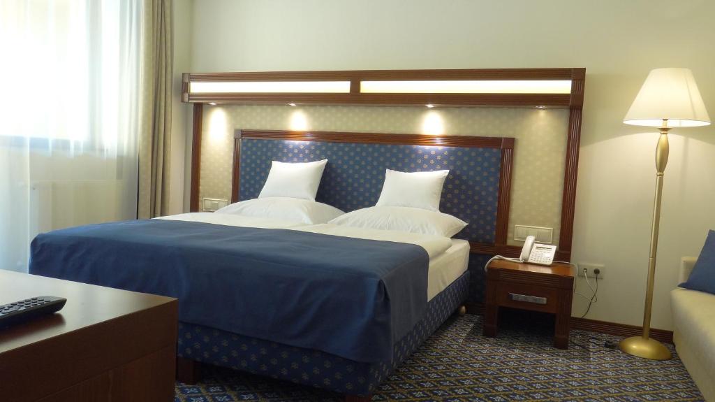 a bedroom with a large bed with a blue blanket at Centrum Hotel in Debrecen