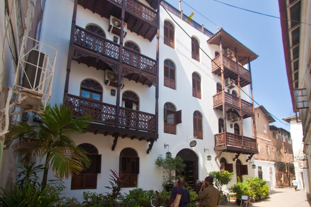 a white building with balconies on a street at Asmini Palace Hotel in Zanzibar City