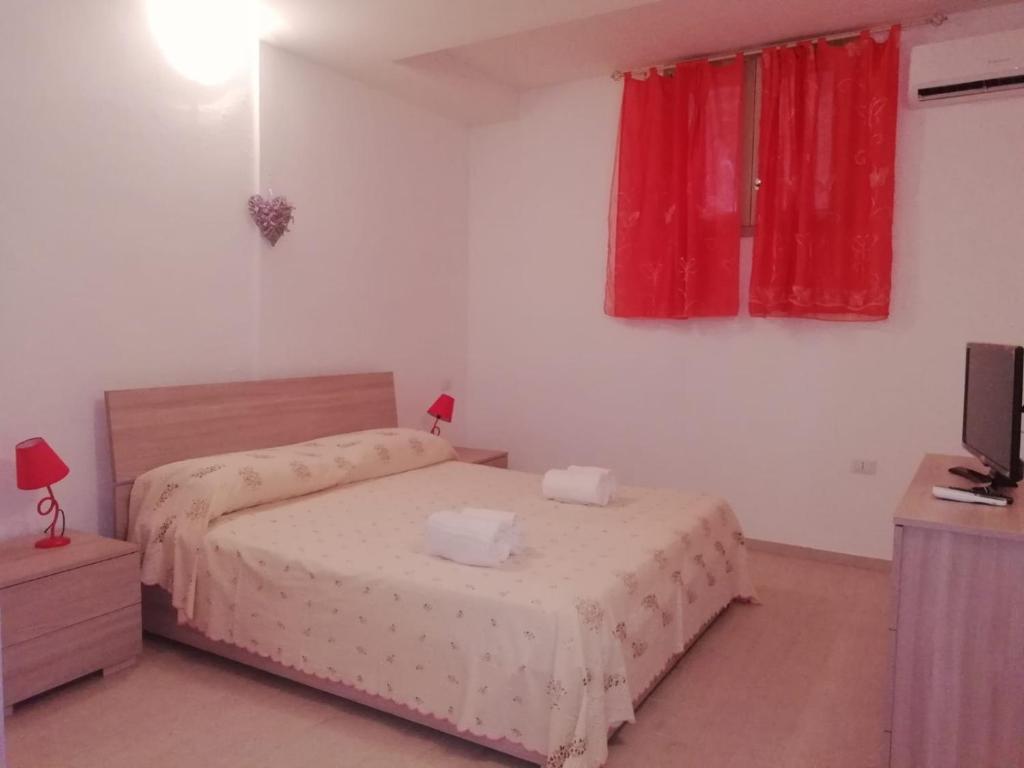 1 dormitorio con 2 camas, cortinas rojas y TV en Casa di Eugenia en Loceri