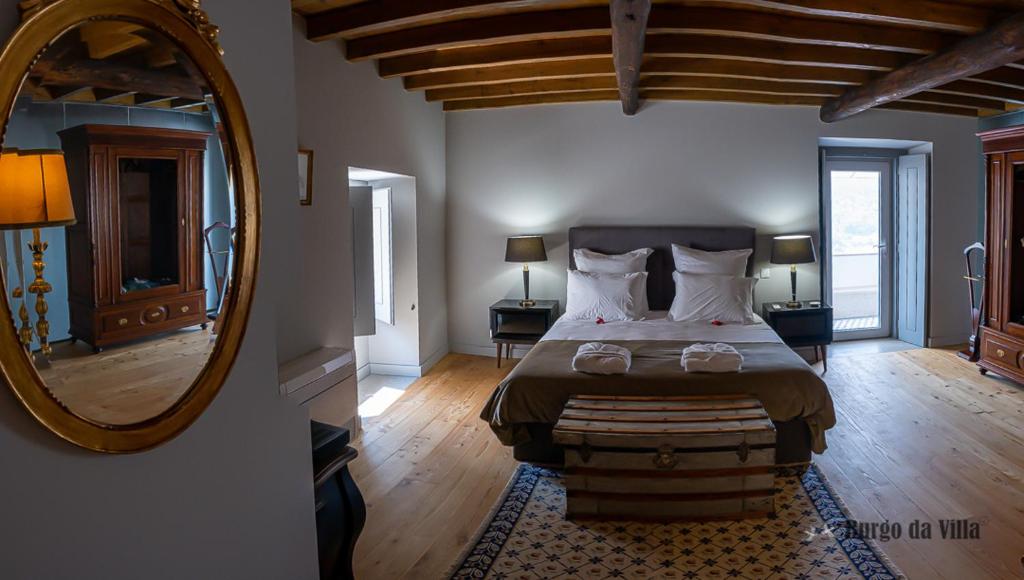 een slaapkamer met een groot bed en een spiegel bij Burgo da Villa in Castelo de Vide