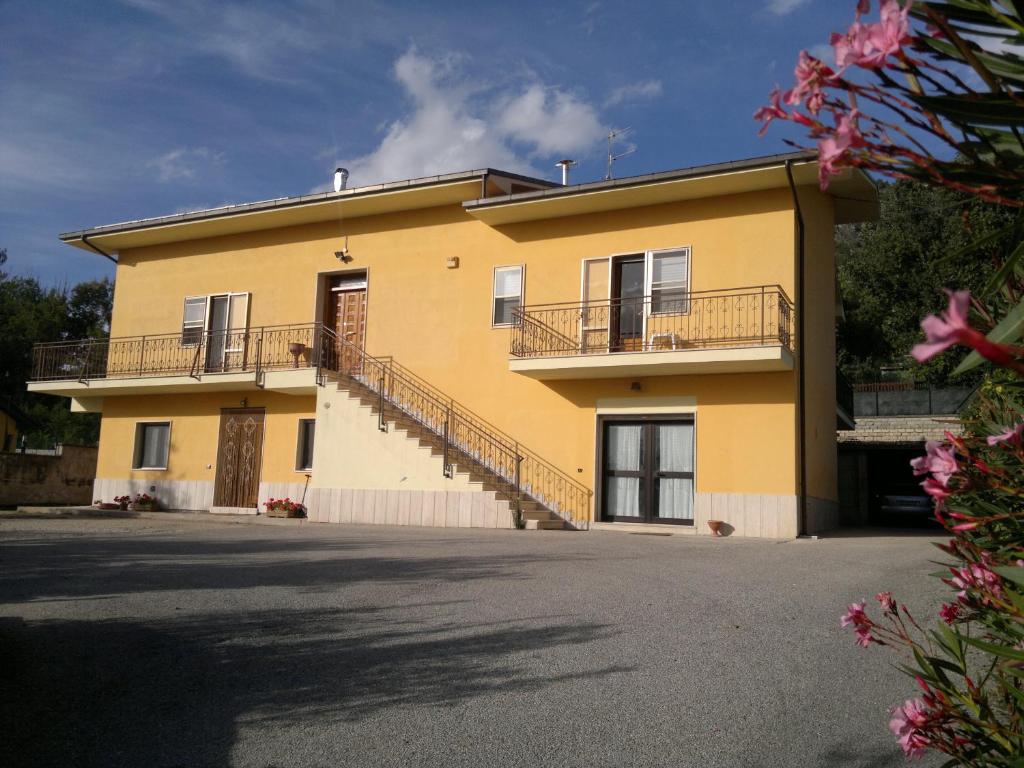 un grande edificio giallo con balconi e vialetto di B&B L'Aquila a L'Aquila