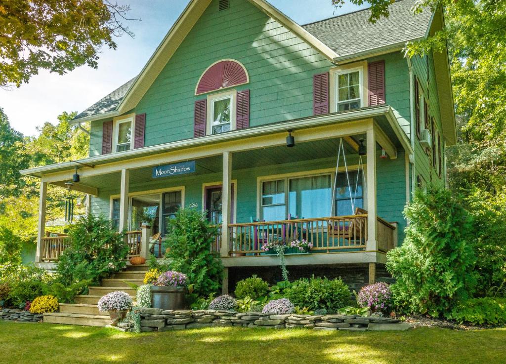 a green house with a porch and a yard at Moonshadow B&B in Hammondsport