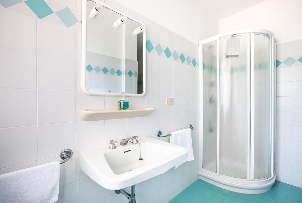 a white bathroom with a sink and a shower at condominio italia in Lignano Sabbiadoro