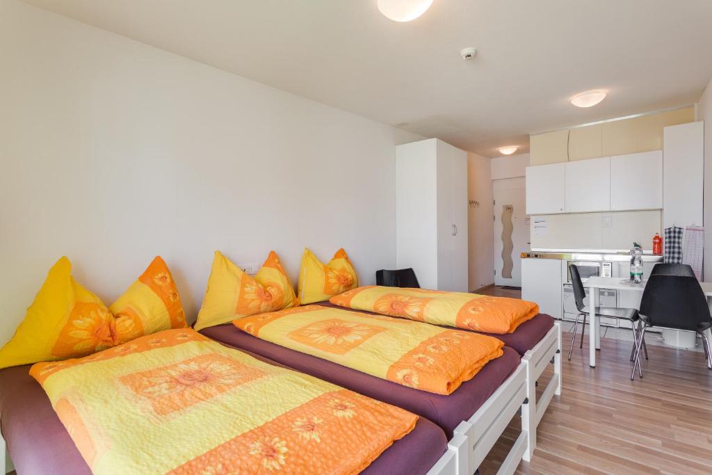 a bedroom with two beds with orange and yellow pillows at Anstatthotel Hochdorf - self-check-in in Hochdorf