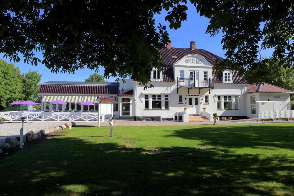 ein großes weißes Haus mit Rasen davor in der Unterkunft Ølsted Kro & Hotel in Ølsted