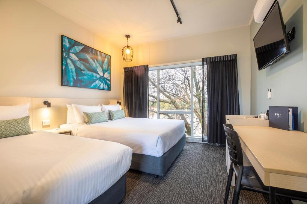 una camera d'albergo con 2 letti e una scrivania di Nightcap at Excelsior Hotel a Melbourne