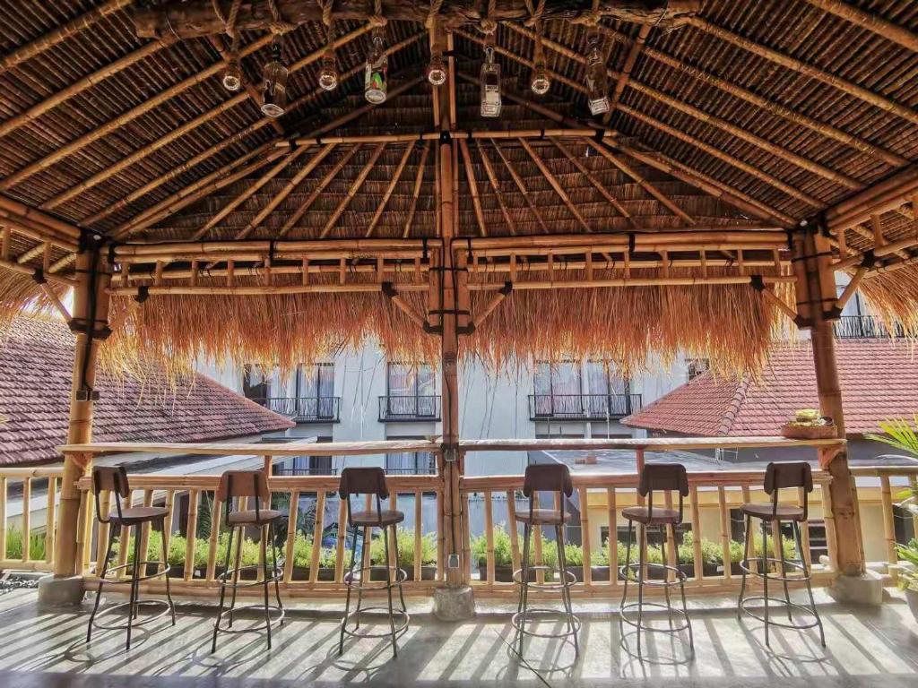 um grupo de bancos de bar sob um guarda-chuva de palha em Nuka Beach Inn em Kuta