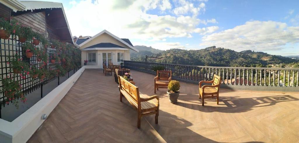 uma varanda com cadeiras de madeira e vista para uma casa em Refúgio das Rosas em Campos do Jordão