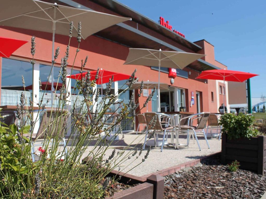 a patio with chairs and umbrellas in front of a building at ibis Albert Pays de Somme in Albert