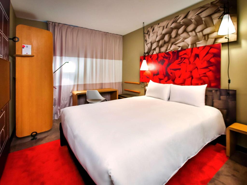 um quarto de hotel com uma grande cama branca com uma cabeceira vermelha em Ibis Rabat Agdal em Rabat