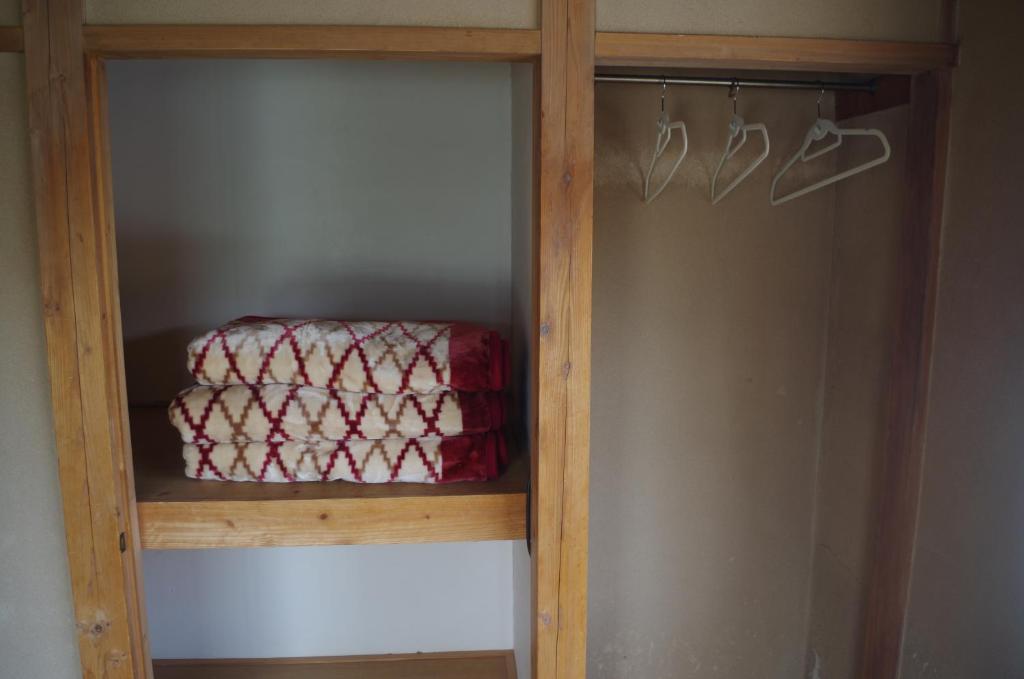 a wooden closet with a red blanket on a shelf at Kusatsu Onsen Guesthouse Gyoten in Kusatsu