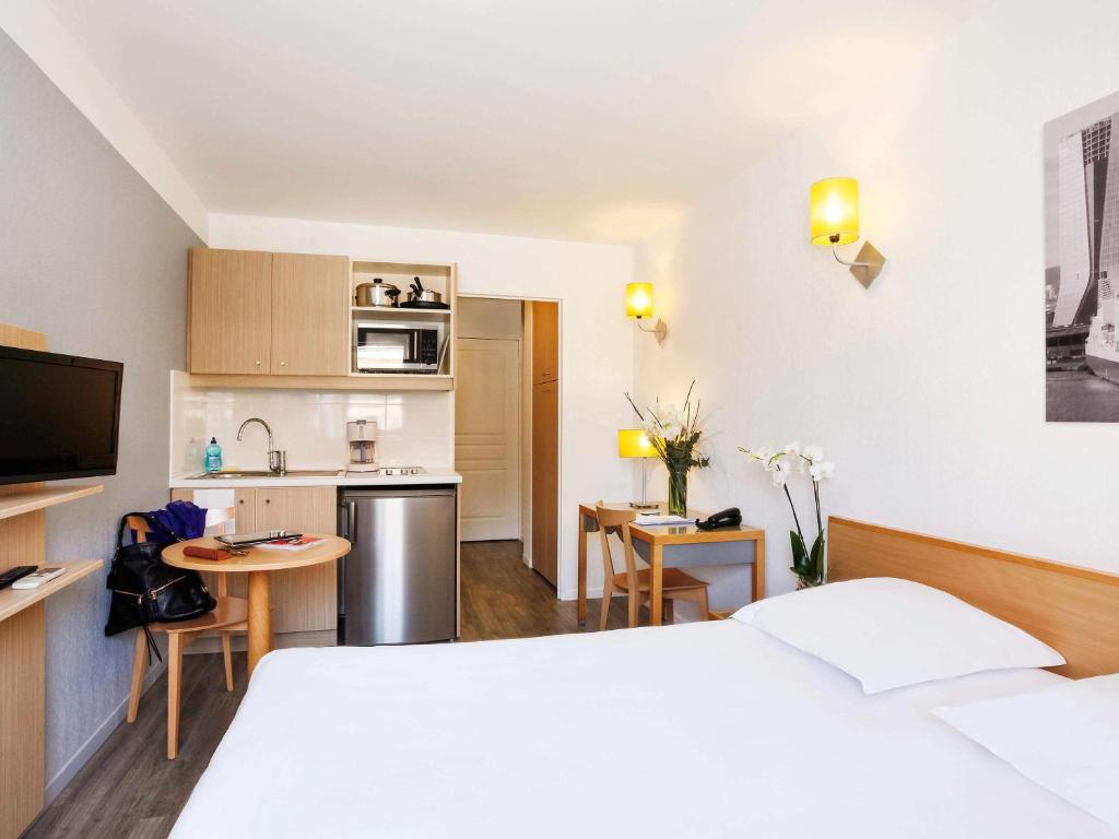 マルセイユにあるアパートホテル アダージョ アクセス マルセイユ プラド ペリエのベッド2台とキッチンが備わるホテルルームです。