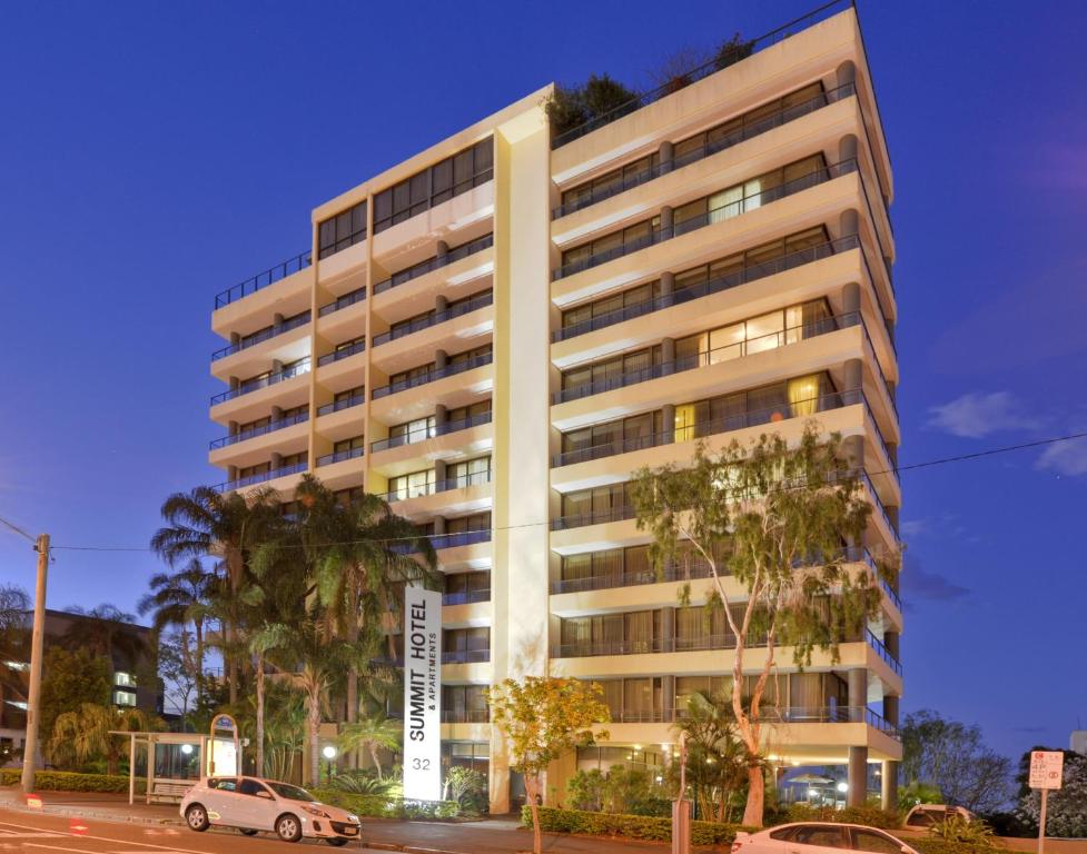 a tall white building with cars parked in front of it at Summit Apartments in Brisbane