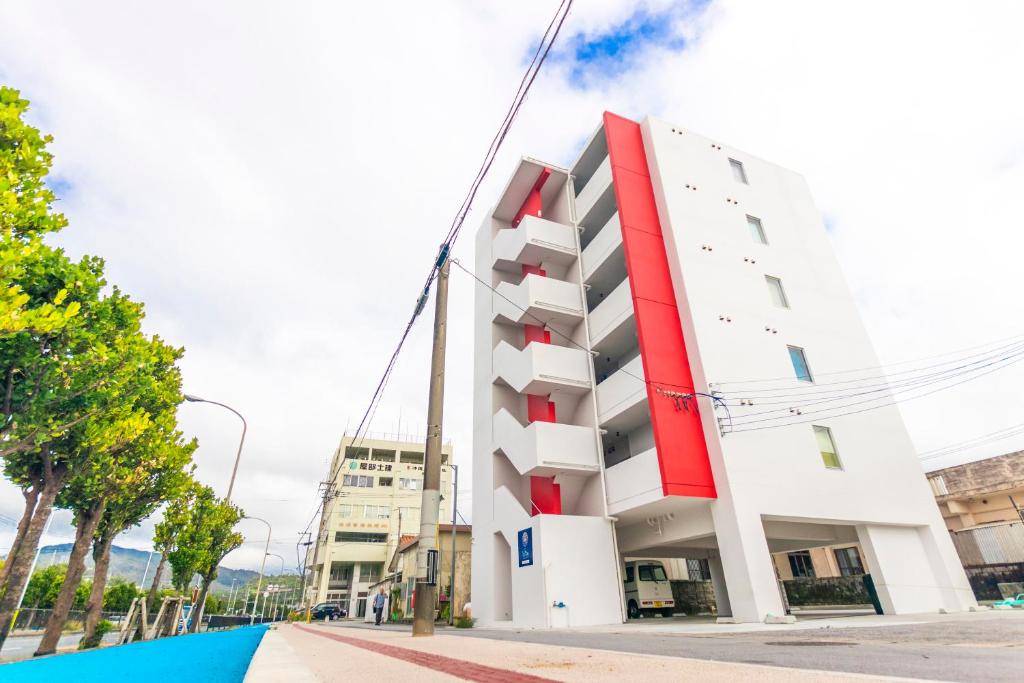 a white and red building on a city street at Hote Io Lite in Nago