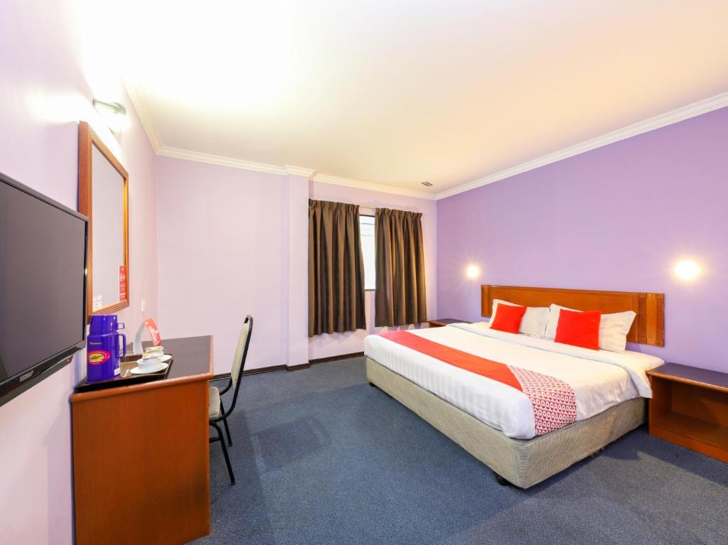 Habitación de hotel con cama, escritorio y TV. en OYO 472 Comfort Hotel 1 en Klang
