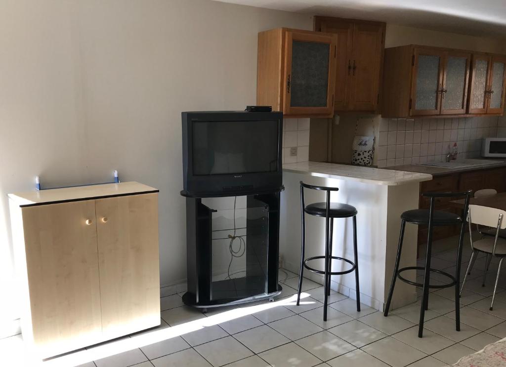 a kitchen with a fireplace with a tv and stools at Studio Meublé in Saint-Thibéry