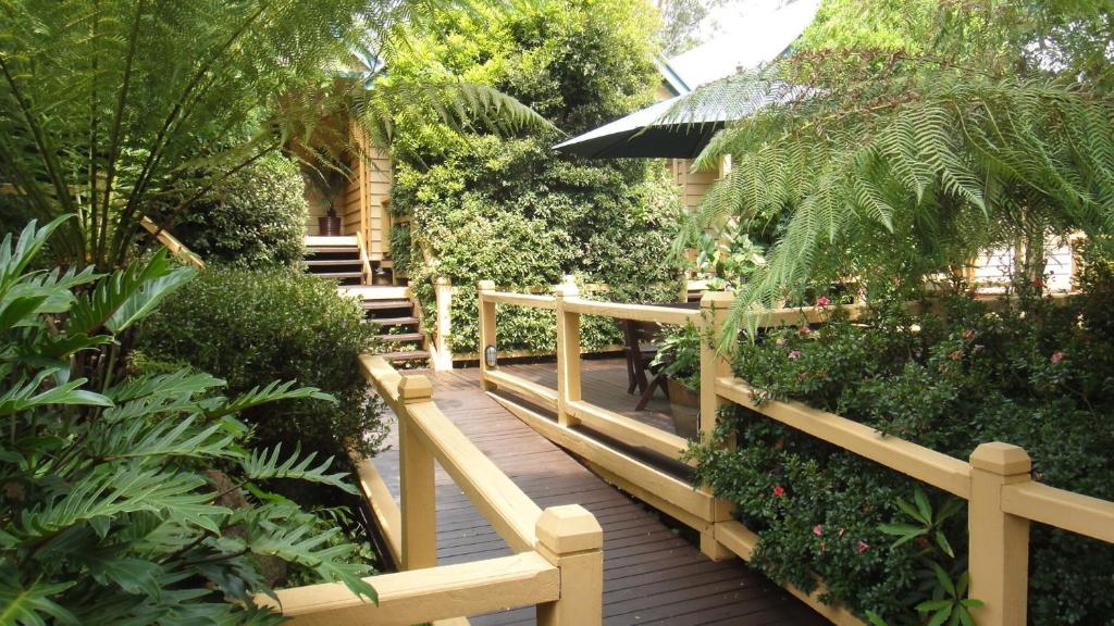 une passerelle en bois dans un jardin avec des plantes dans l'établissement Heritage Trail Lodge, à Margaret River Town