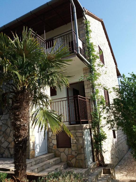 a building with a palm tree in front of it at Apartmani Lupi 2 M&S in Vrboska