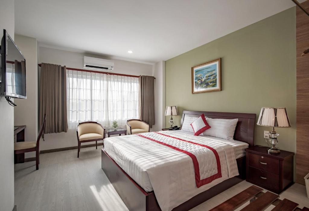 um quarto com uma cama, uma secretária e uma televisão em Hue My Hotel em Ho Chi Minh