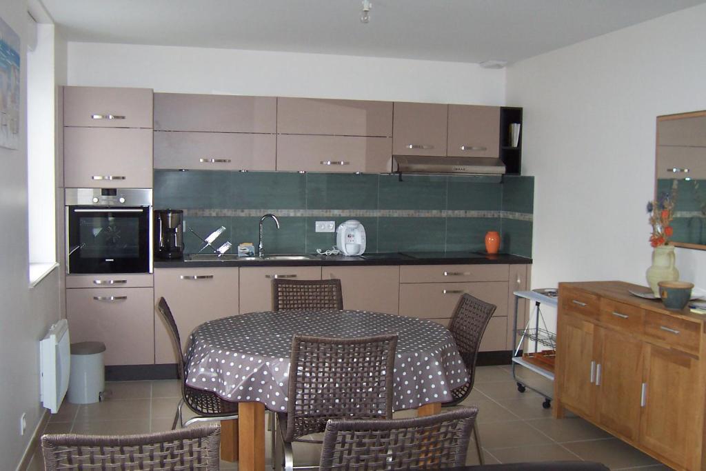 a kitchen with a table and chairs and a kitchen with a counter at La Prairie in Saint-Pair-sur-Mer
