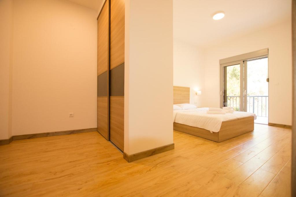 a bedroom with a bed and a large window at Trsteno Beach Apartments in Budva