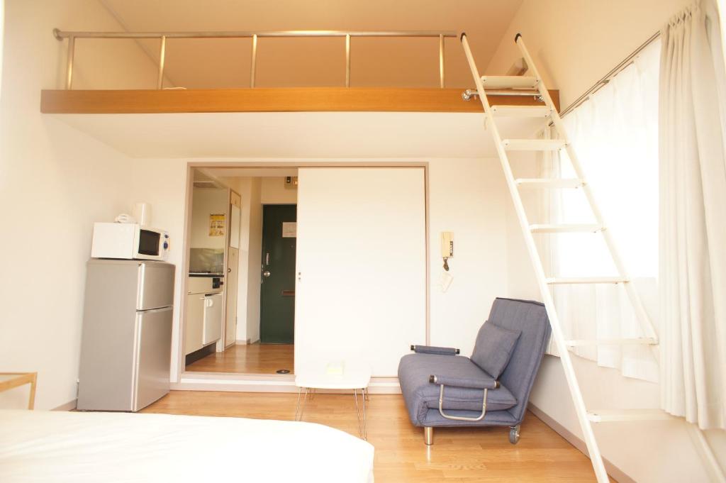 a bedroom with a loft bed and a chair at Plusone Fujisaki in Fukuoka