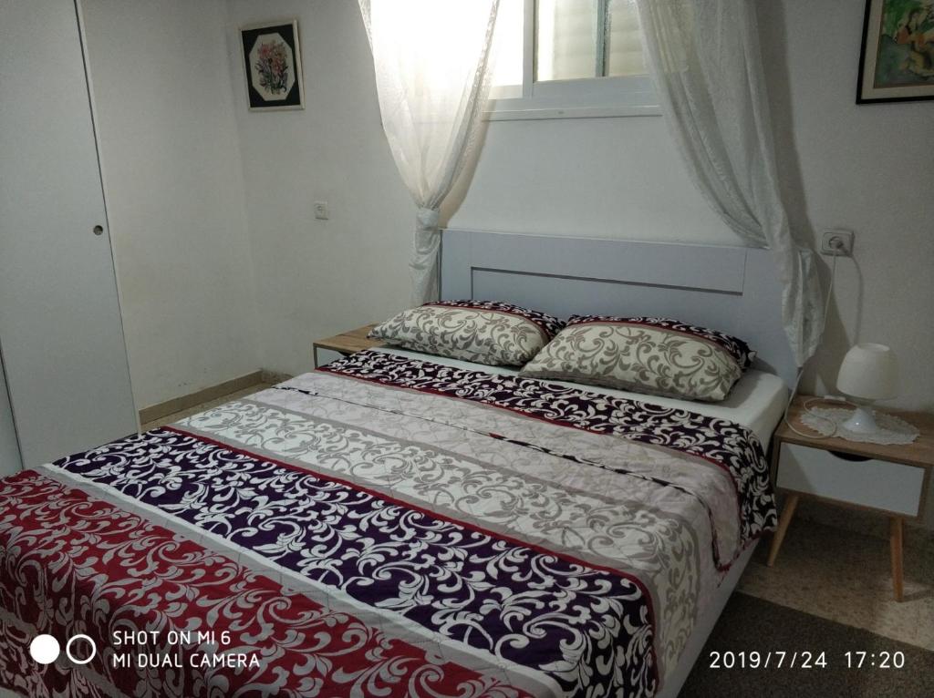 a bed in a small room with a window at Didi Guest House in Bet Sheʼan