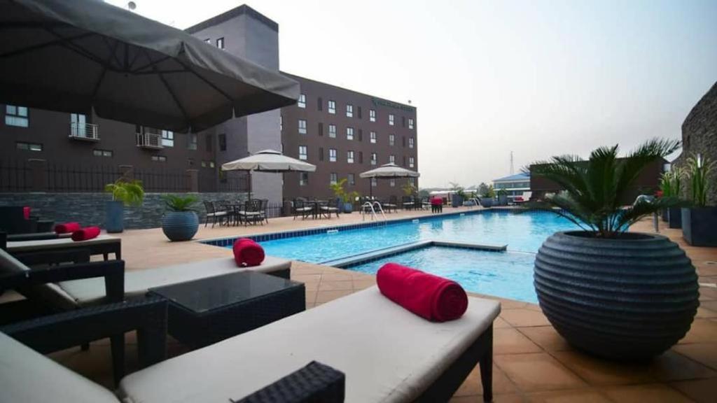 a swimming pool with chairs and a vase with a plant at Oak Plaza Suites in Kumasi