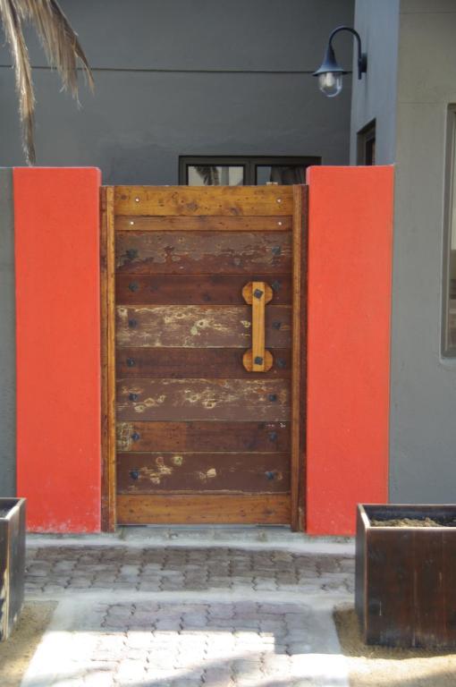 una gran puerta de madera con una pared roja en SelkieBnB en Walvis Bay