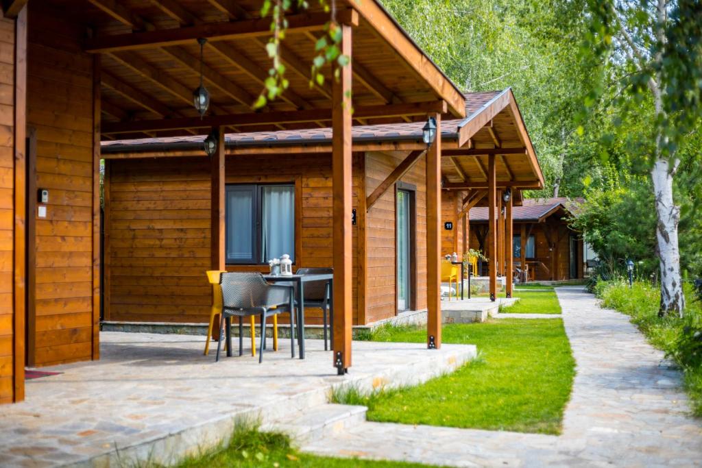 a wooden cabin with a table and chairs in front of it at Friends Bungalows in Kŭrdzhali
