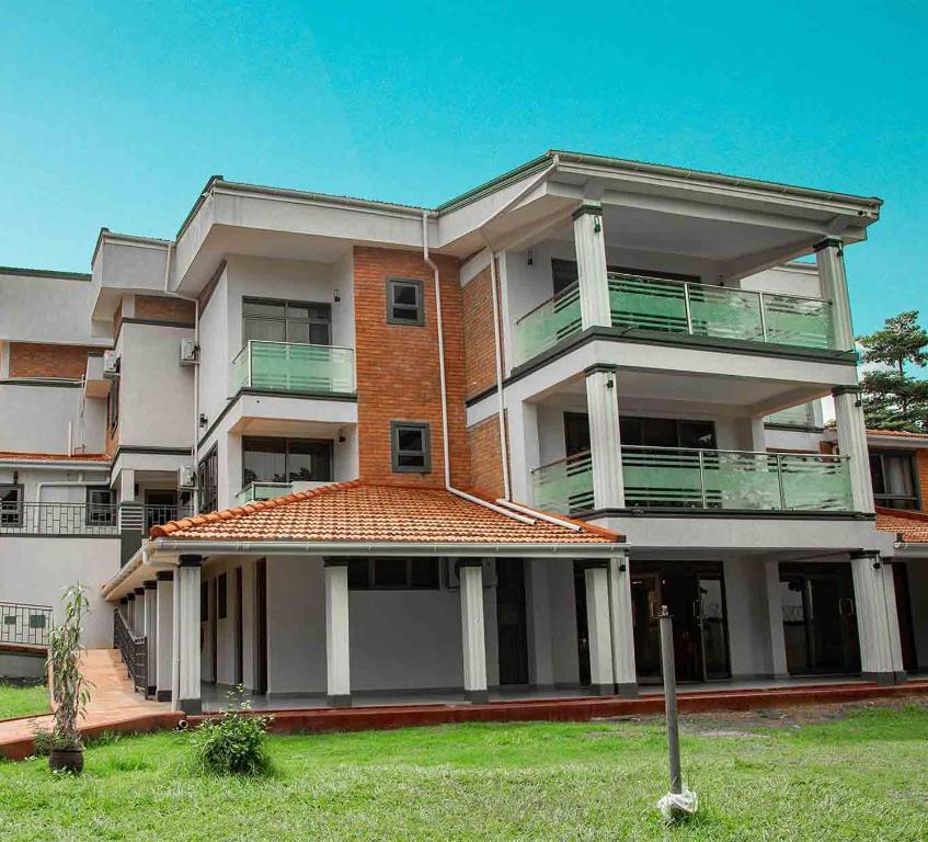 a large apartment building with a green lawn in front of it at Emmaus Guesthouse Kampala in Kampala