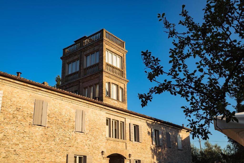 una torre de reloj alta en la parte superior de un edificio de ladrillo en Il Pignocco Country House, en Santa Veneranda
