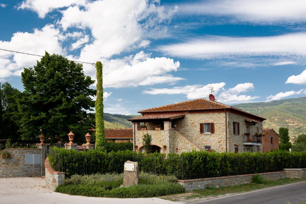 uma casa de pedra com uma cerca em frente em Fattoria del Nonno Berto em Cortona