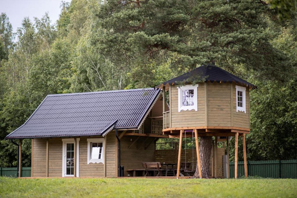 a tree house with a porch and a balcony at Sodyba Namelis medyje Anykščiuose in Anykščiai