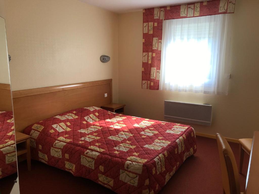 a hotel room with a bed and a window at Hôtel La Colombiere Cantal in Massiac