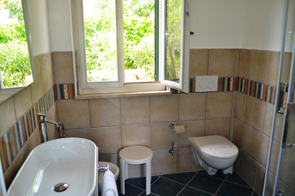 a bathroom with a sink and a toilet and two windows at Hotel Danila in Portoferraio