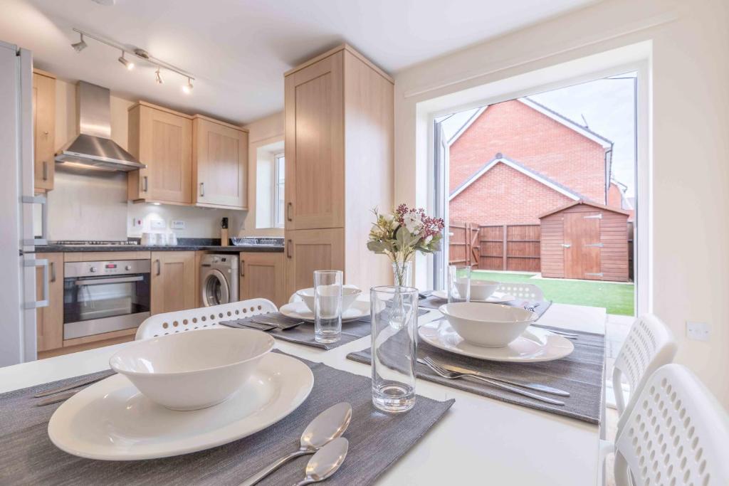 a kitchen with a table with plates and bowls on it at WINDSOR 10 MINS - 3 DOUBLE BEDROOM & 2 BATHROOM HOUSE WITH PARKING in Slough