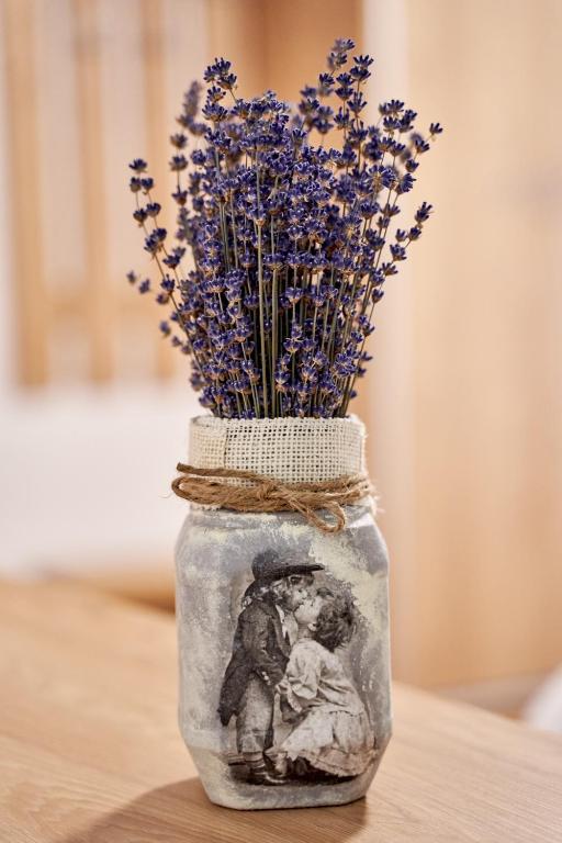 a glass jar with purple flowers in it on a table at Lavand House in Vişeu de Sus
