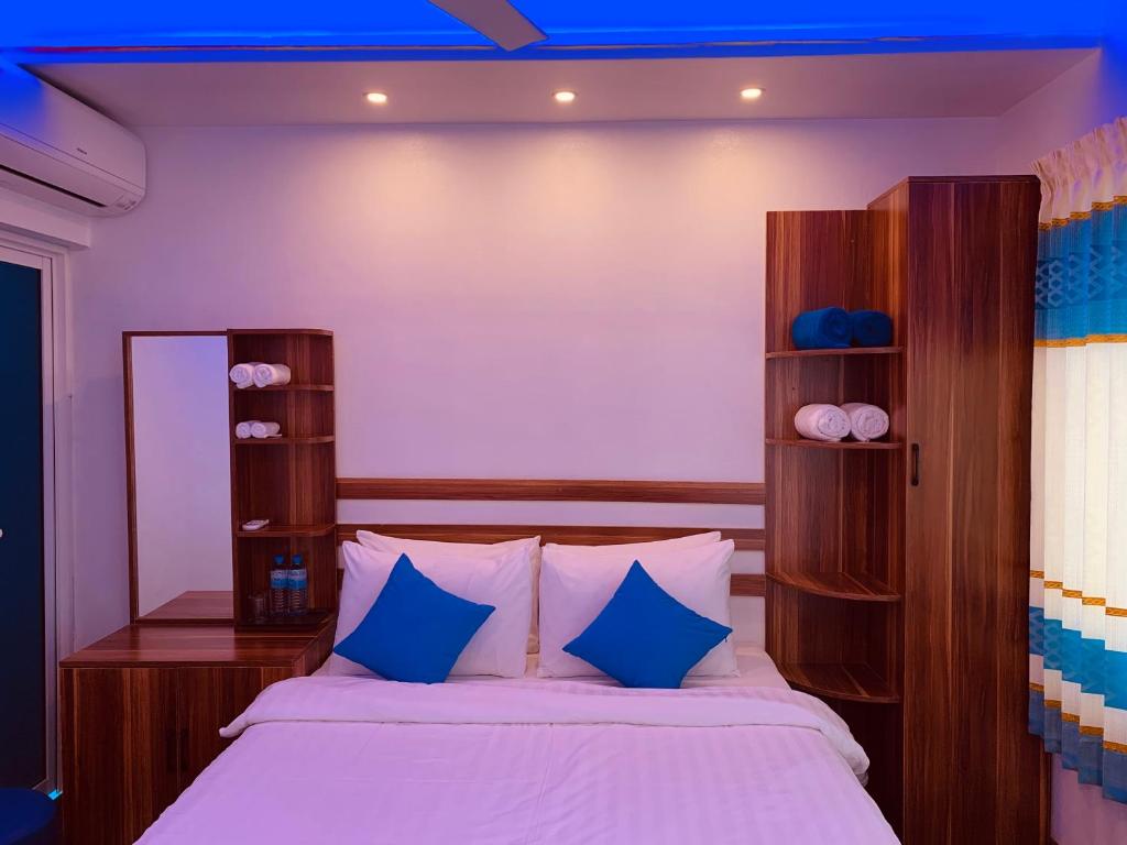 a bedroom with a large bed with blue pillows at Hudhuvelimaldives in Omadhoo